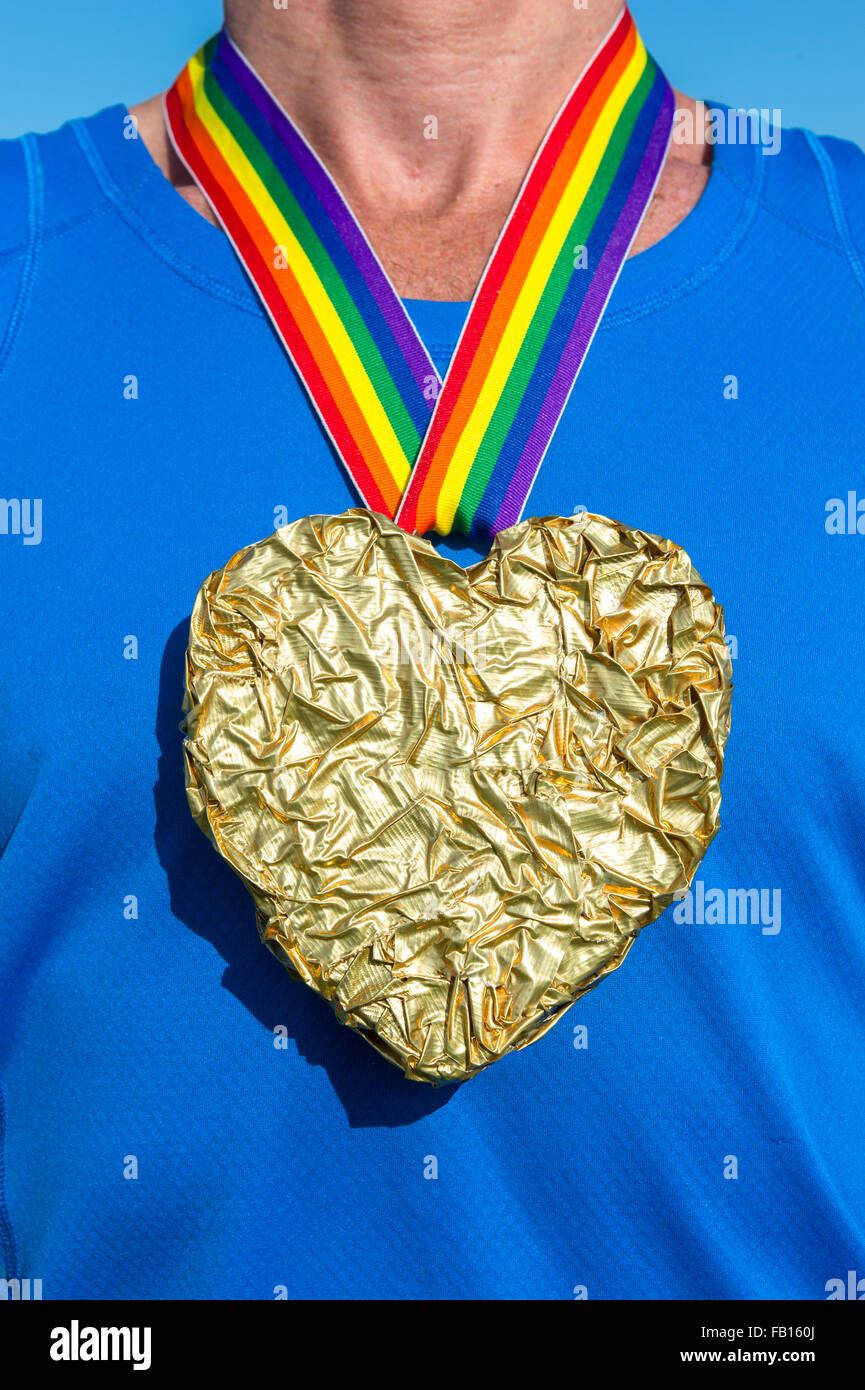 Gay athlete standing with heart gold medal and rainbow ribbon against blue  sky close-up Stock Photo - Alamy