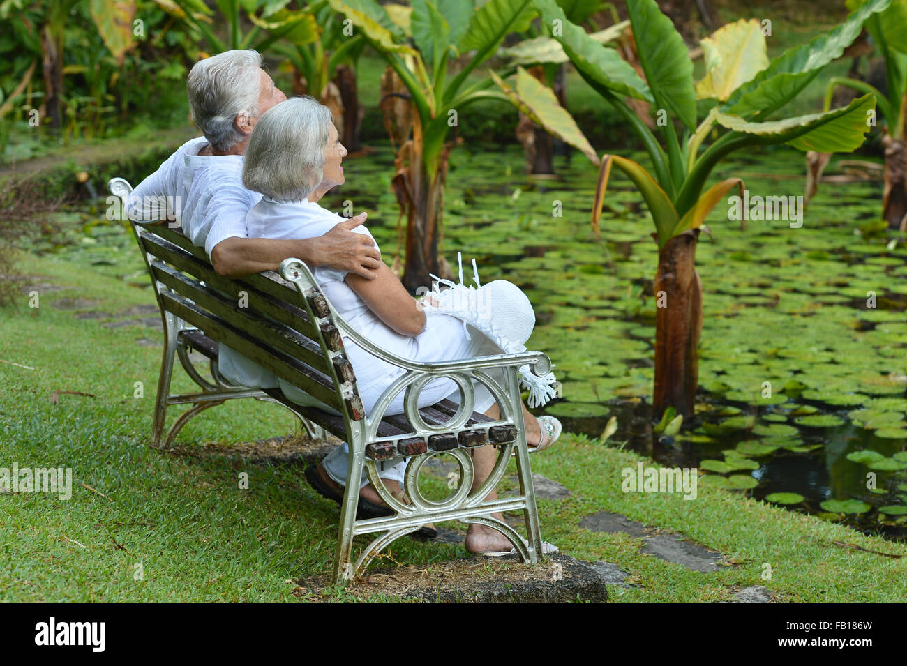 Elderly couple sitting on a bench outdoors Stock Photo - Alamy