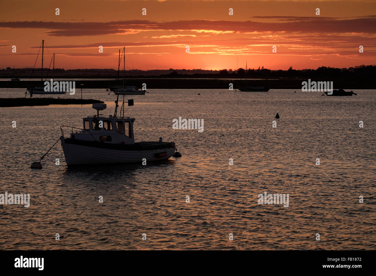 Small boat at sunset on Hamford backwater Stock Photo