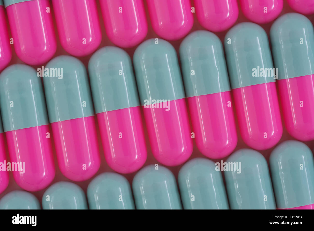Close-up of pills - capsule form made of gelatin. Pink / Grey pills. Metaphor taking on American drug companies over high drug prices, drug trials. Stock Photo