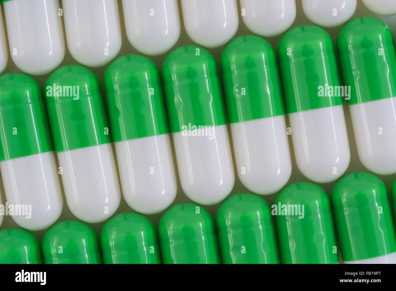 Close-up of pills - capsule form made of gelatin. Green / White pills. Metaphor taking on American drug companies over high drug prices, drug trials. Stock Photo