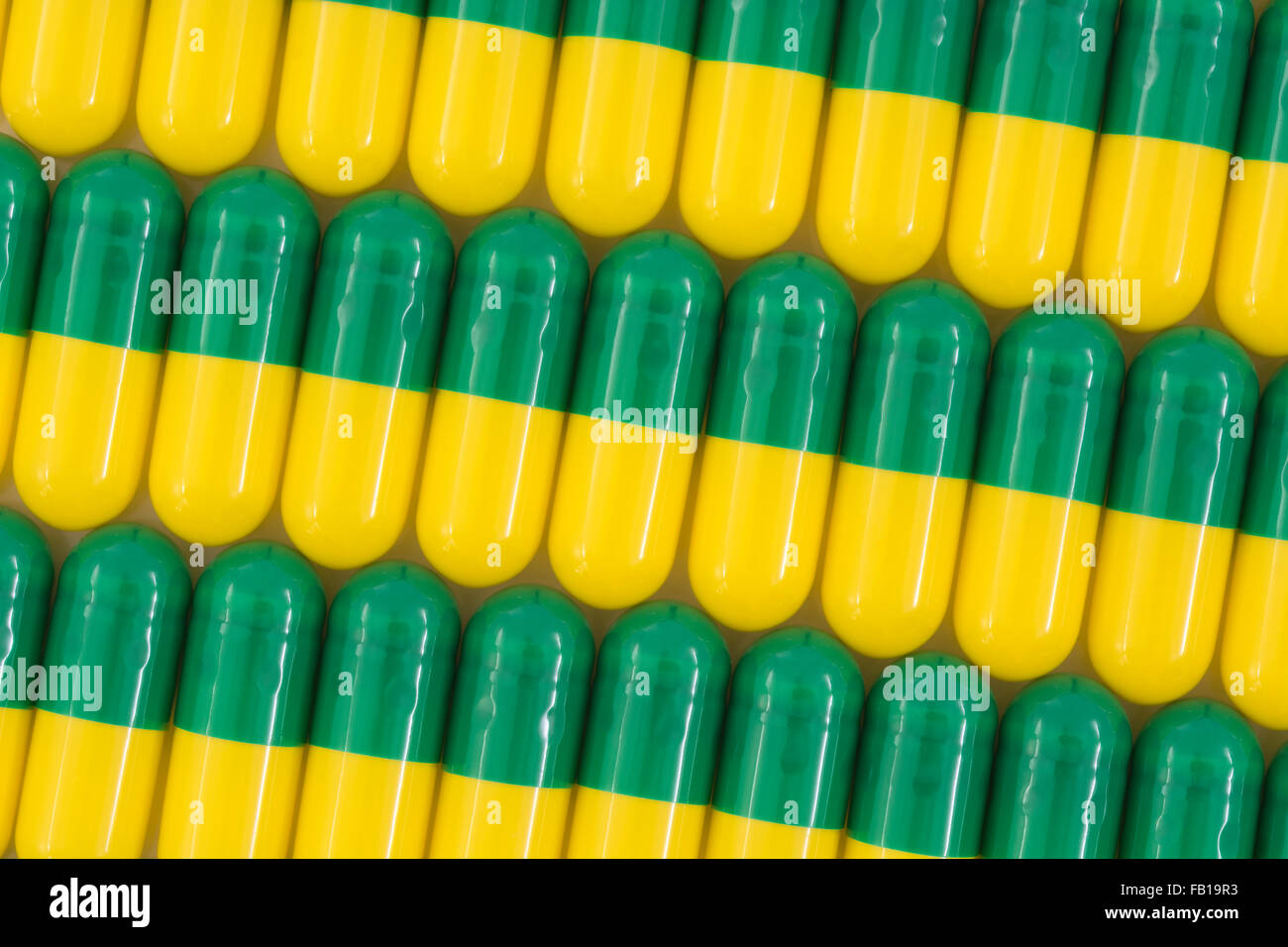 Close-up of pills - capsule form made of gelatin. Green / Yellow pills. Metaphor taking on American drug companies over high drug prices, drug trials. Stock Photo