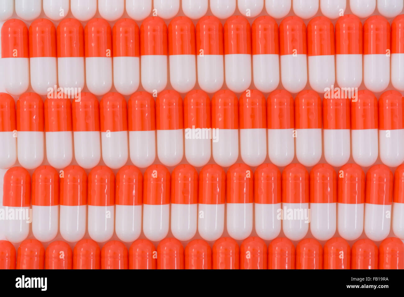 Close-up of pills - capsule form made of gelatin. Orange / White pills. Metaphor taking on American drug companies over high drug prices, drug trials. Stock Photo