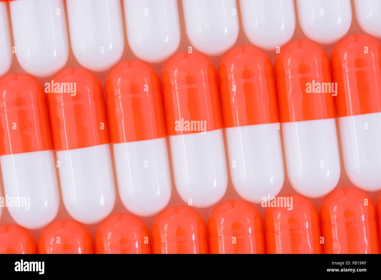 Close-up of pills - capsule form made of gelatin. Orange / White pills. Metaphor taking on American drug companies over high drug prices, drug trials. Stock Photo