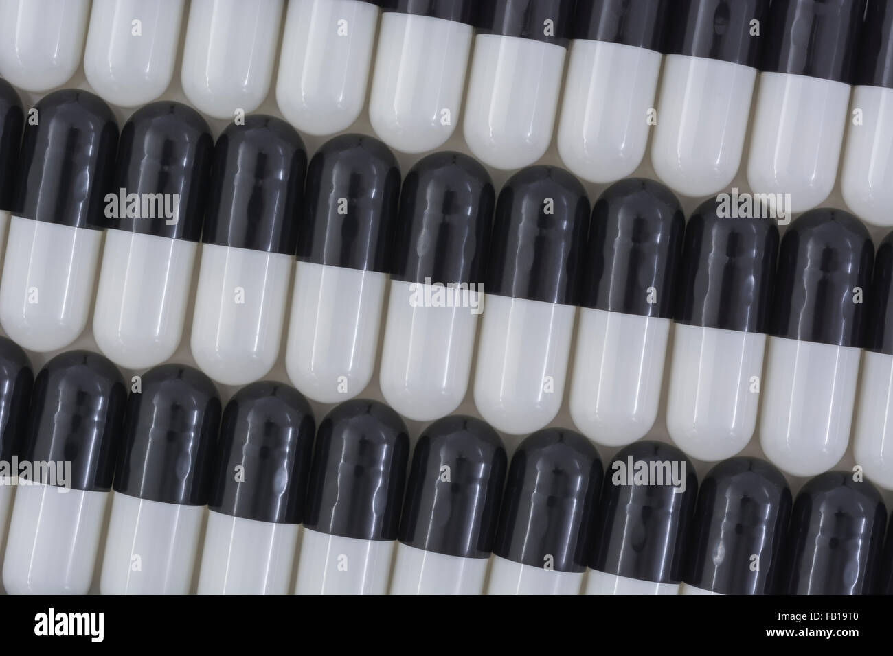 Closeup of pills capsule form made of gelatin. Black / White pills. Metaphor taking on