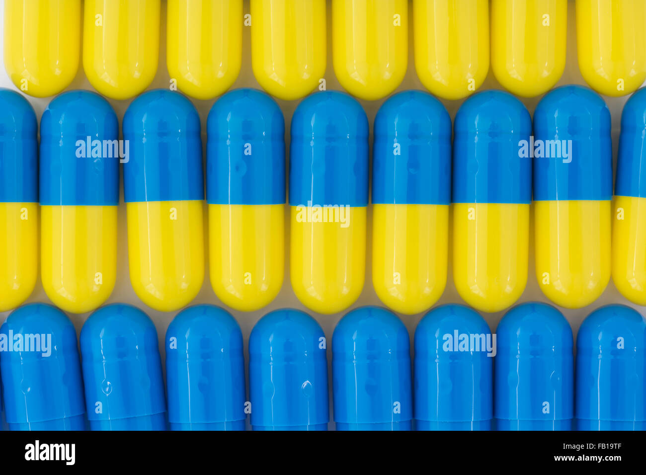 Close-up of pills - capsule form made of gelatin. Blue / Yellow pills. Metaphor taking on American drug companies over high drug prices, drug trials. Stock Photo