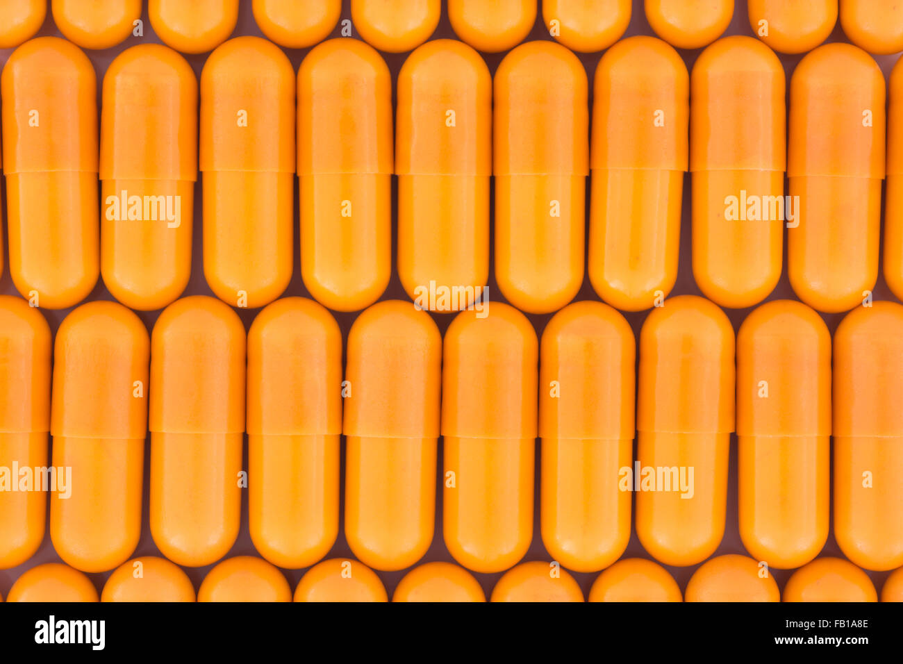 Close-up of orange pills - capsule form made of gelatin (these orange ones are a vegetarian form of capsule). Metaphor taking on drug companies. Stock Photo