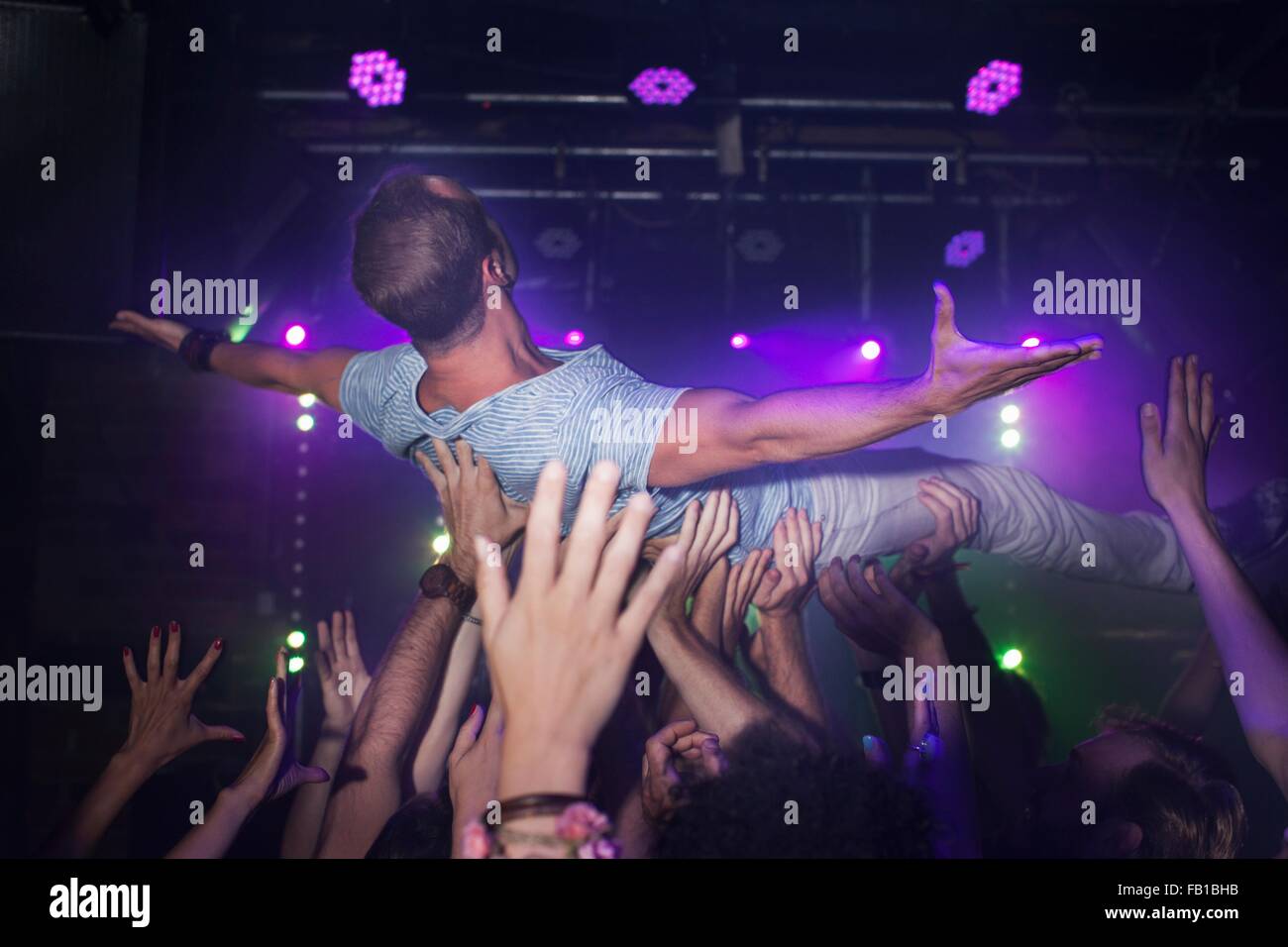 Group of people lifting man in club Stock Photo