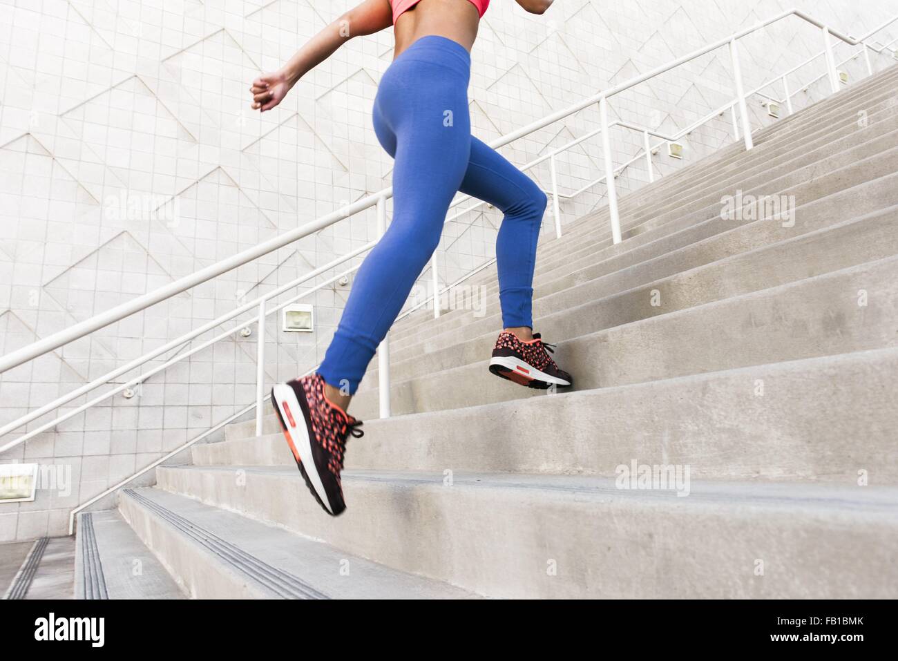 Low angle rear view of young woman, wearing sports clothing running up stairs Stock Photo
