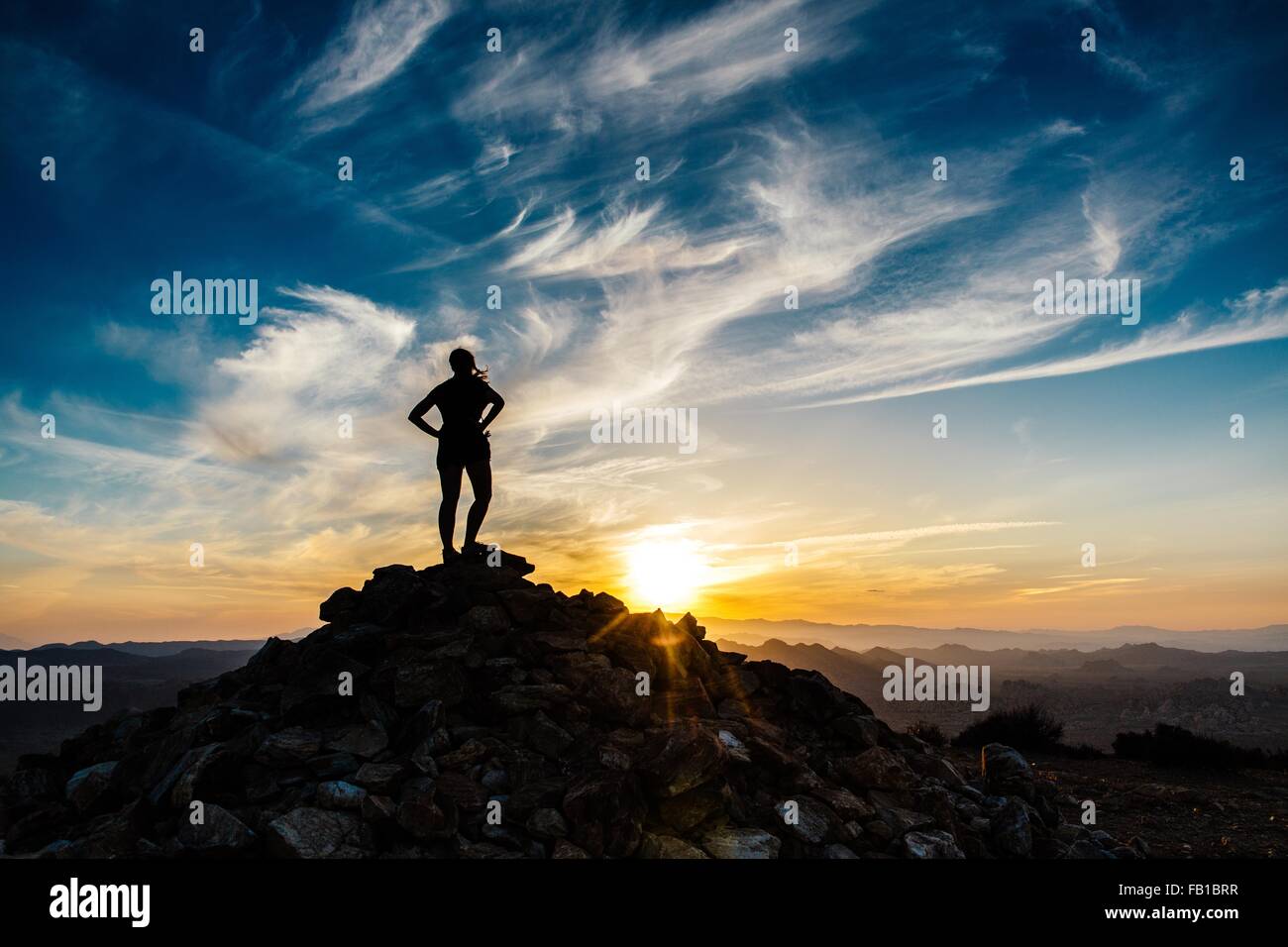 Silhouette mid adult woman mountain top sunset rear view Ryan Mountain Hiking Trail Joshua Tree National Park California USA Stock Photo