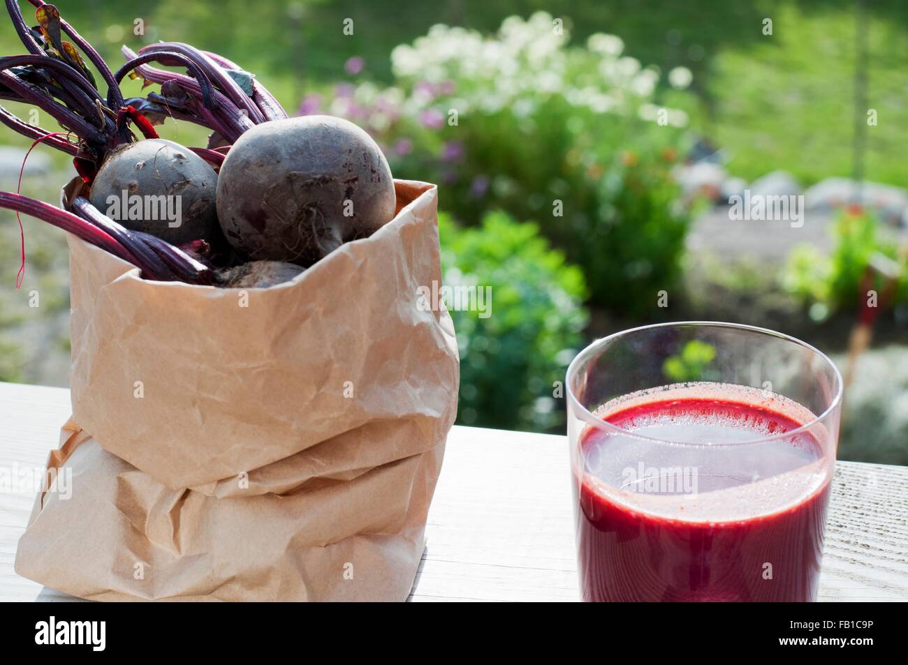 Bag of organic beetroot and glass of beetroot juice on garden table Stock Photo