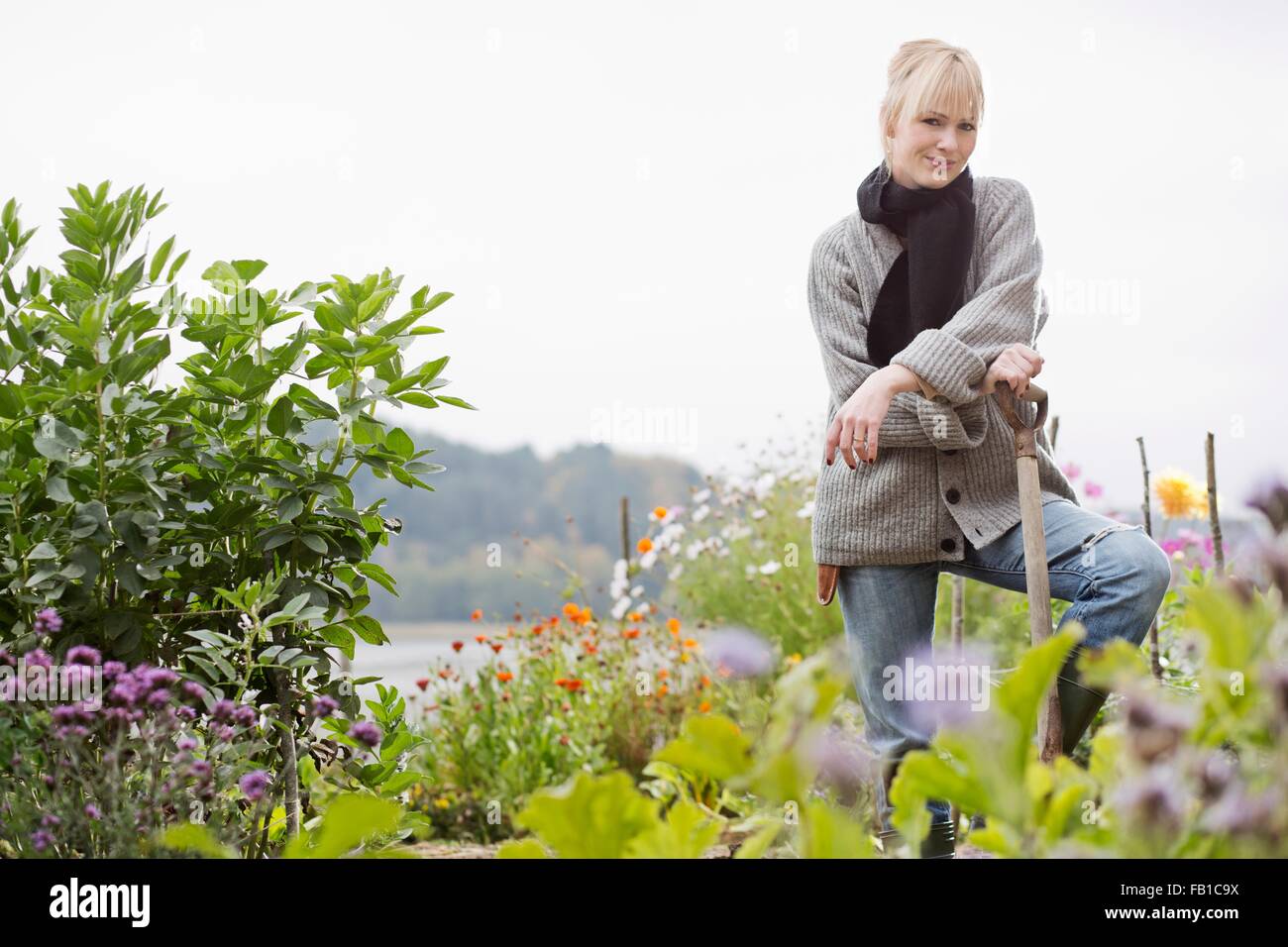 Portrait of mid adult woman digging in organic garden Stock Photo