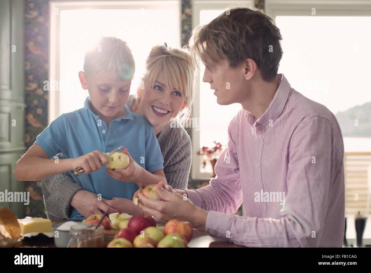 Parents and son peeling organic apples in kitchen Stock Photo