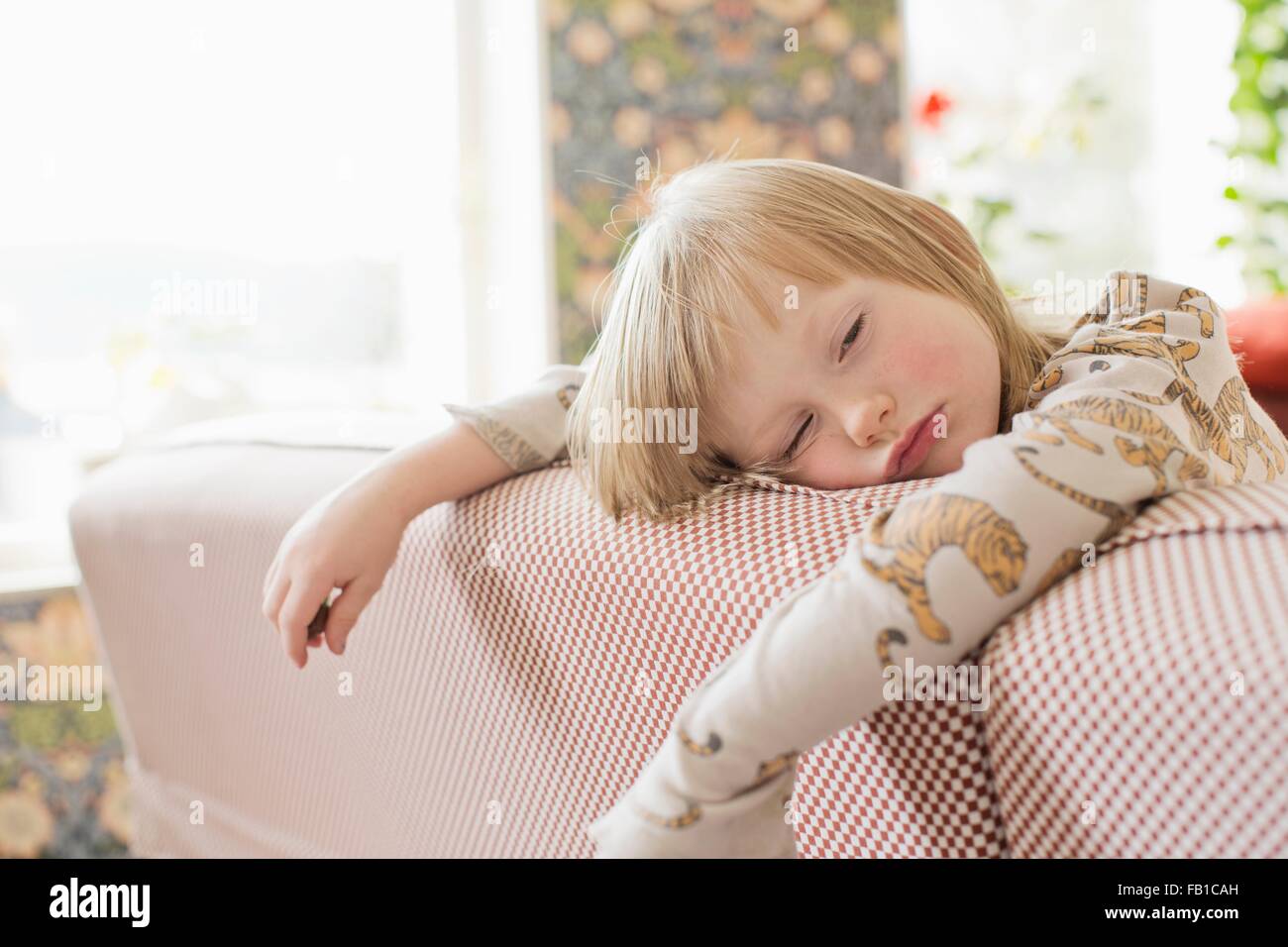 Portrait of sleepy boy leaning on living room sofa Stock Photo