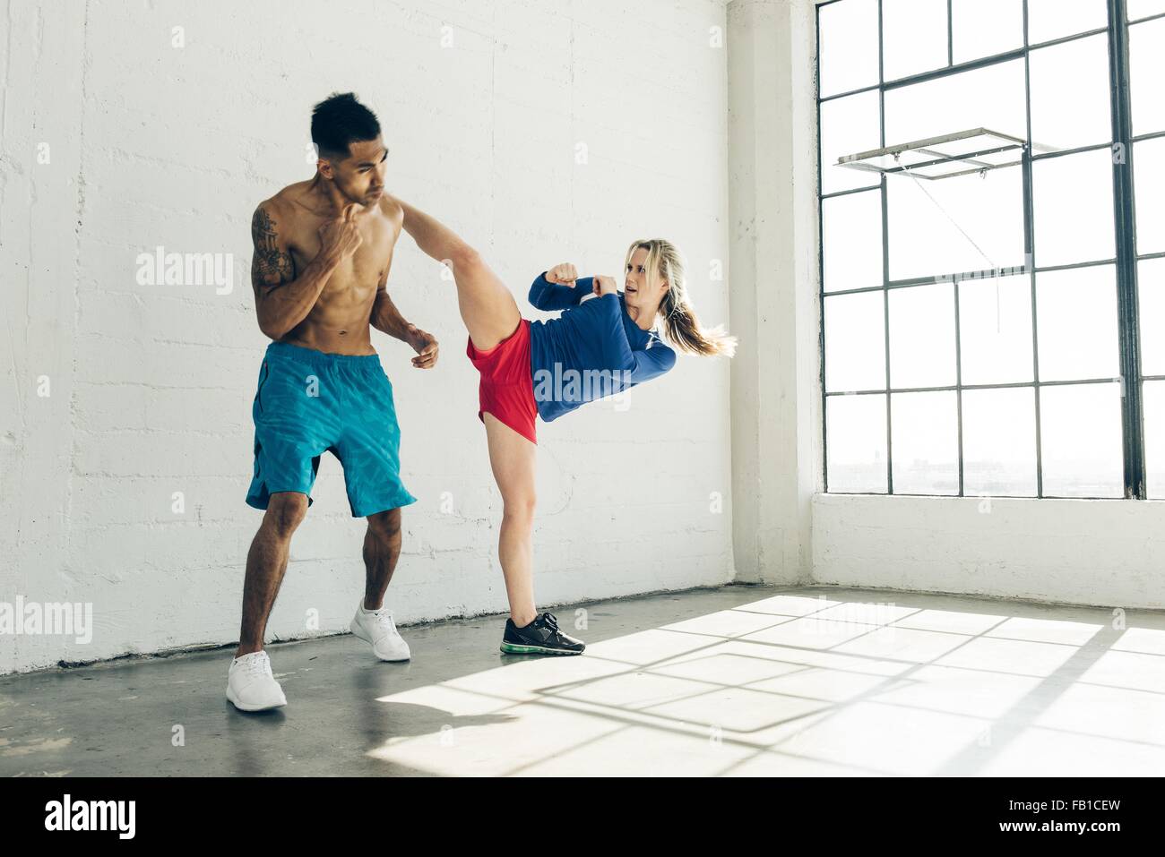Couple in gym, leg raised, kickboxing Stock Photo