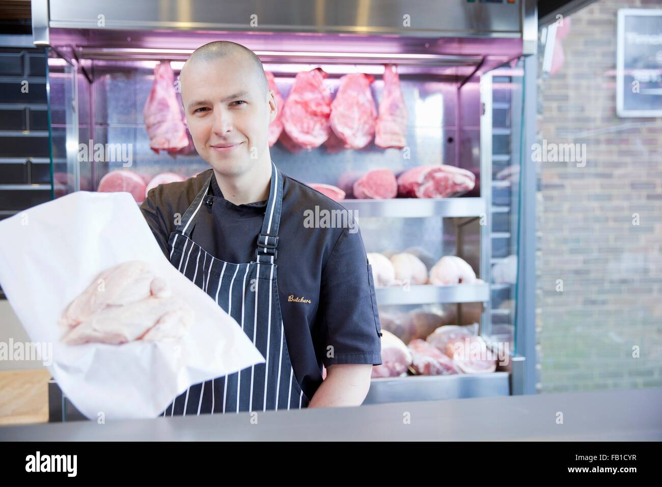 Portrait of butcher holding chicken breast in butchers shop Stock Photo