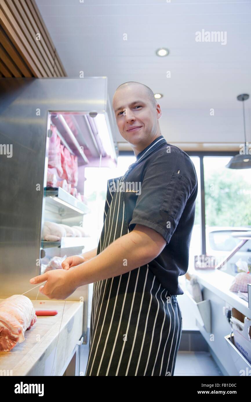 Portrait of butcher tying meat joint in butchers shop Stock Photo