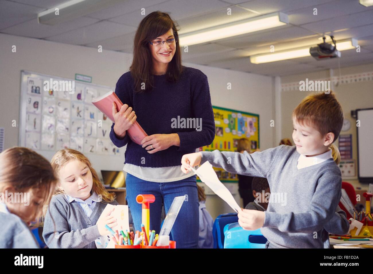 Female teacher with children drawing in elementary school classroom Stock Photo