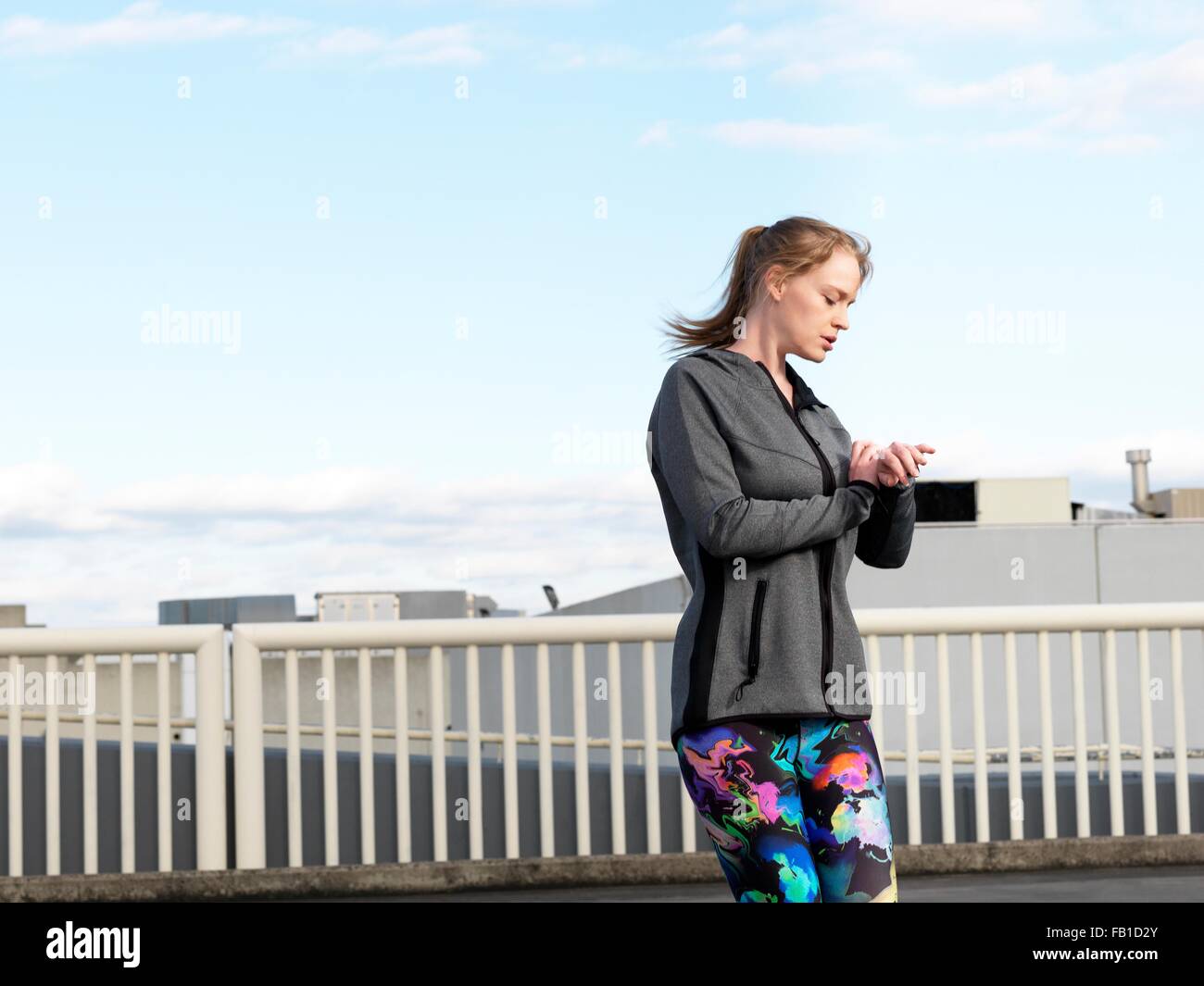 Young woman checking watch whilst training in parking lot Stock Photo