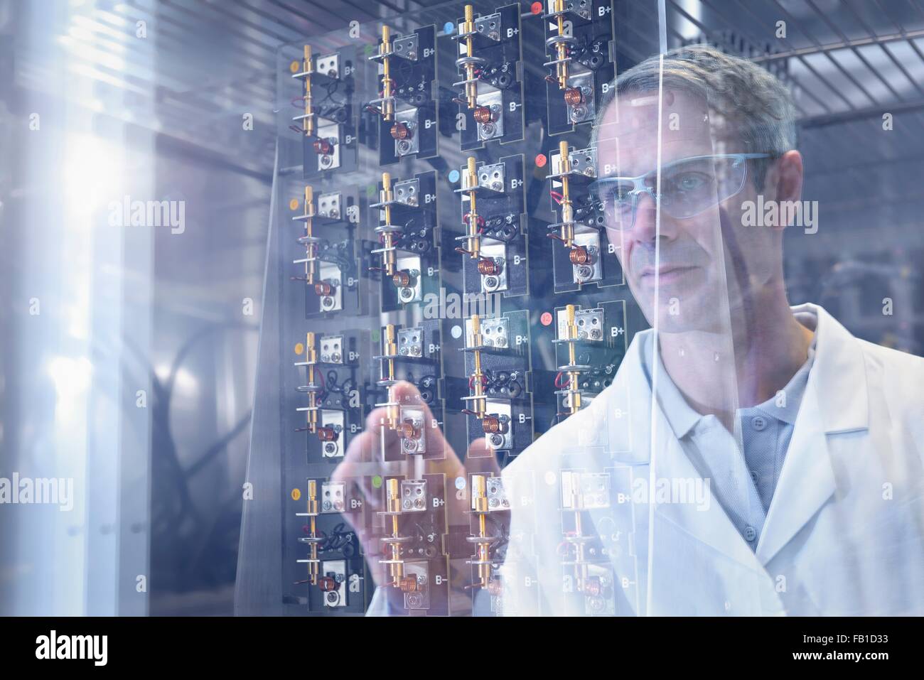 Scientist inspecting test lithium ion batteries in heat chamber in battery research facility Stock Photo