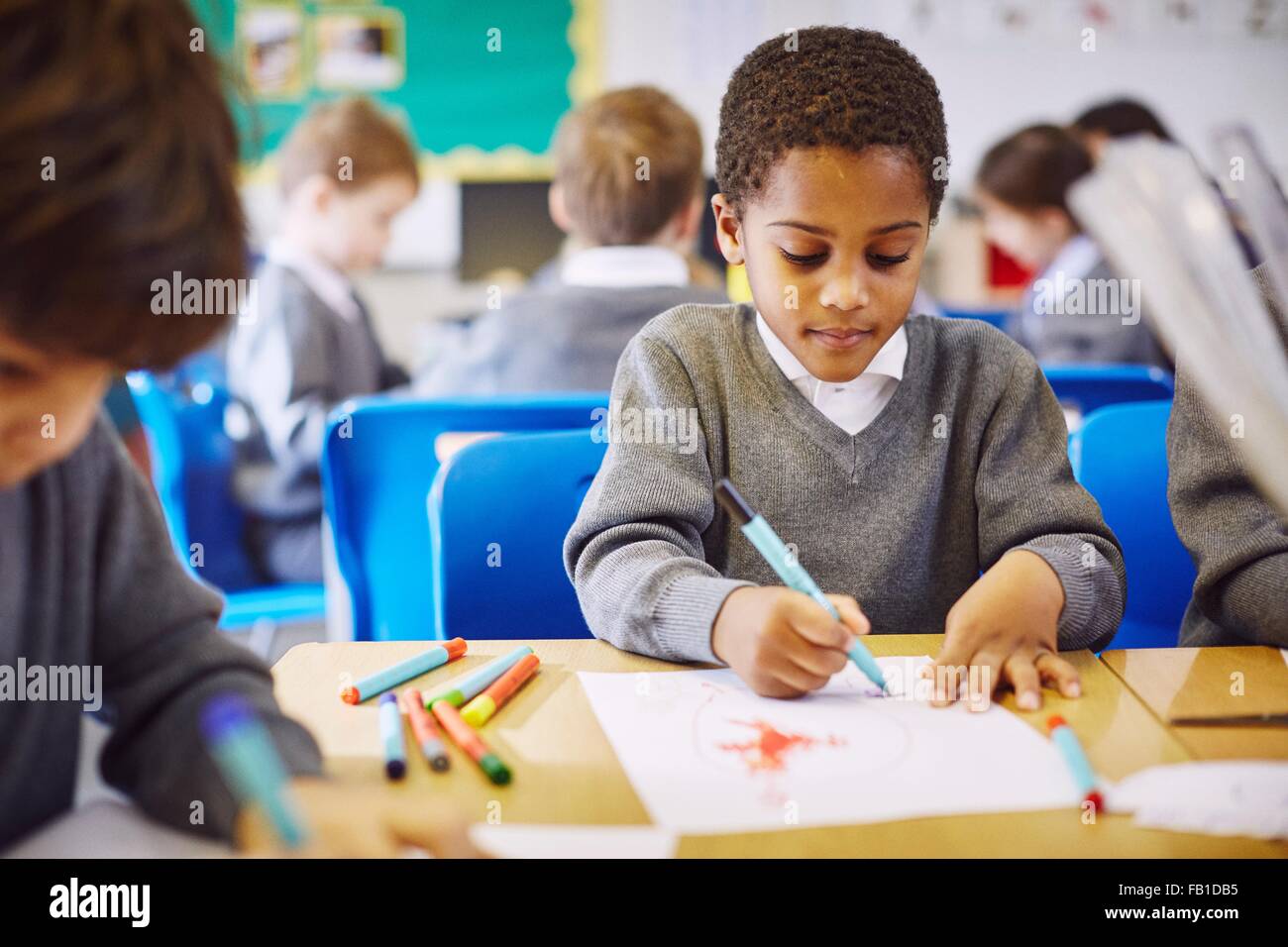 Boys drawing at desks in elementary school classroom Stock Photo