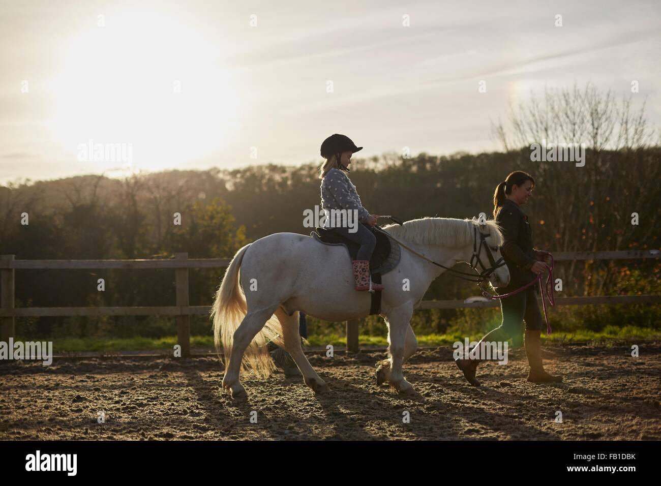 Instructor leading girl riding pony in equestrian arena Stock Photo Alamy