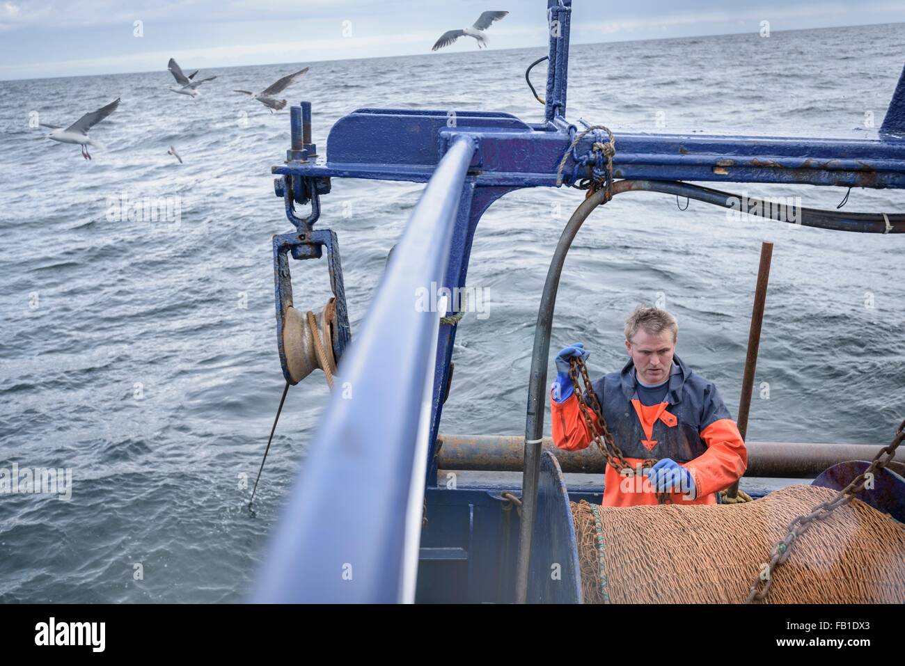 Fisherman preparing net on trawler Stock Photo
