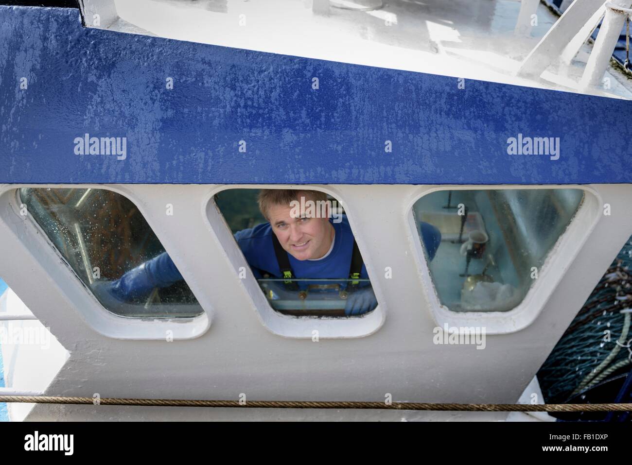 Portrait of trawler captain looking out of window of wheel house Stock Photo