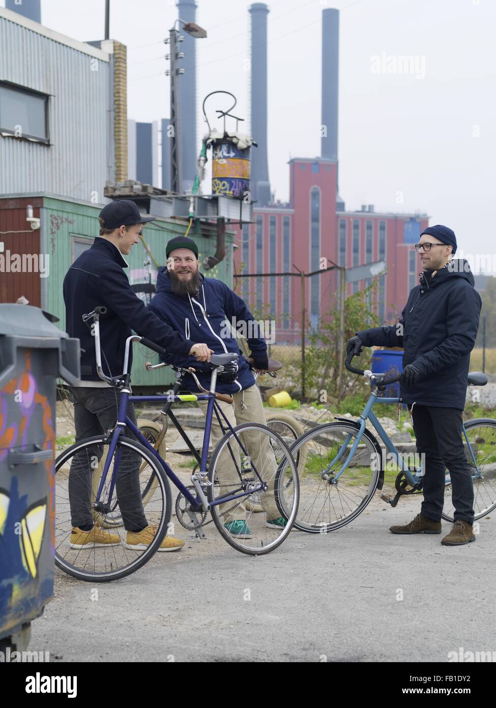 Urban cyclists chatting near factory Stock Photo