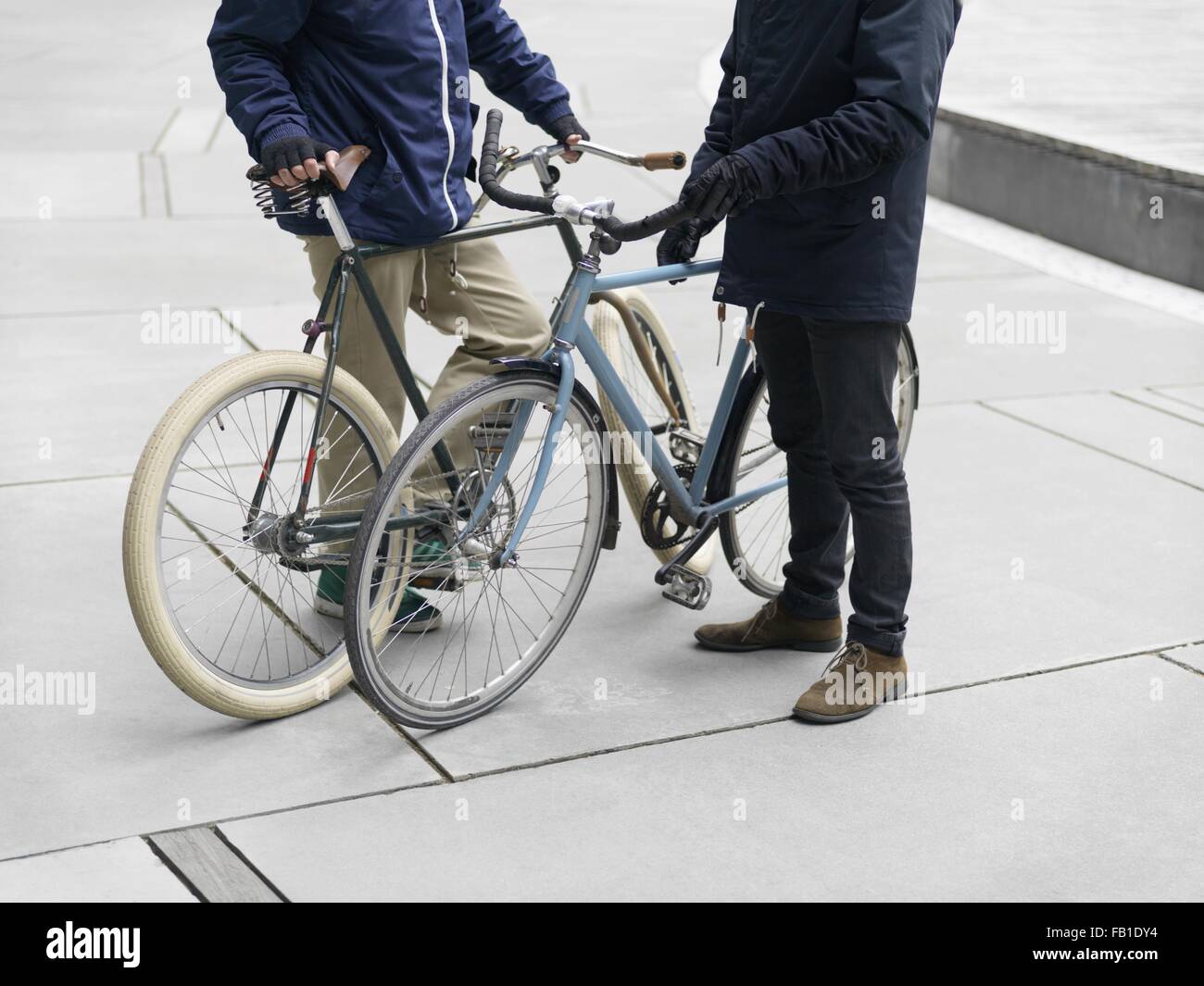 Neck down view of urban cyclists standing beside bicycle Stock Photo