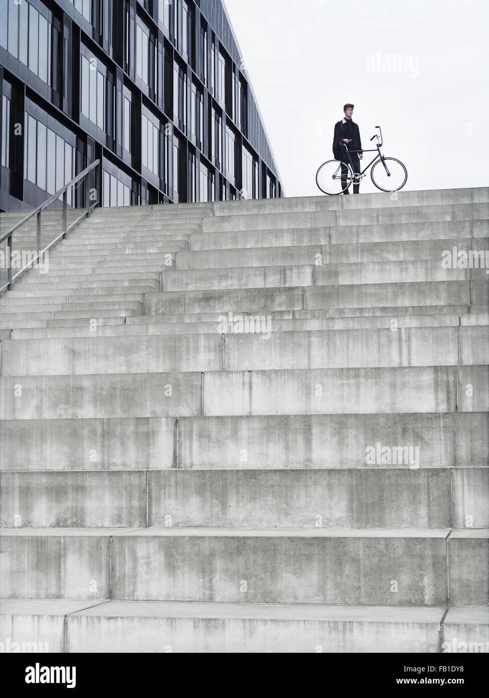 Urban cyclist with bicycle standing on top of stairway Stock Photo