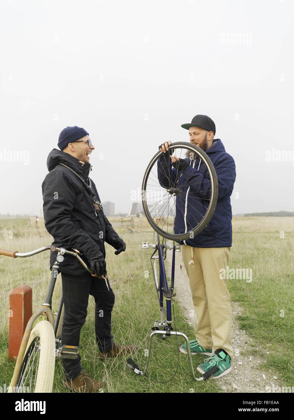 Urban cyclists fixing tyre in field Stock Photo