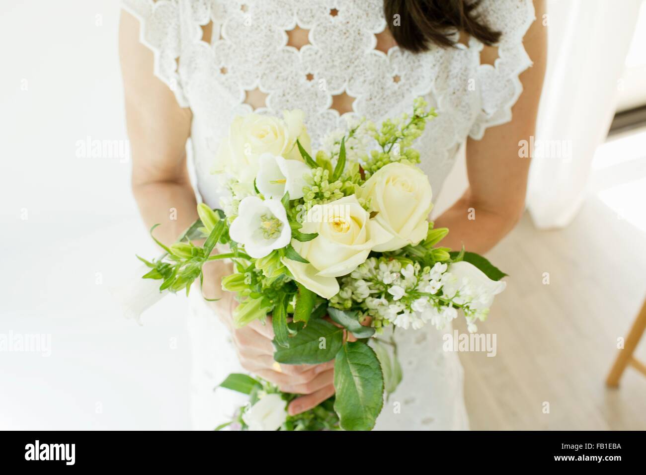 High angle view of mature woman wearing broderie anglaise holding flower arrangements Stock Photo