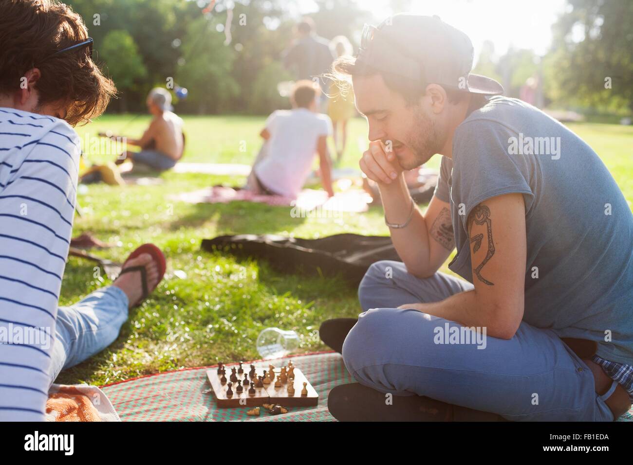 Young adults playing board game at sunset party in park Stock Photo