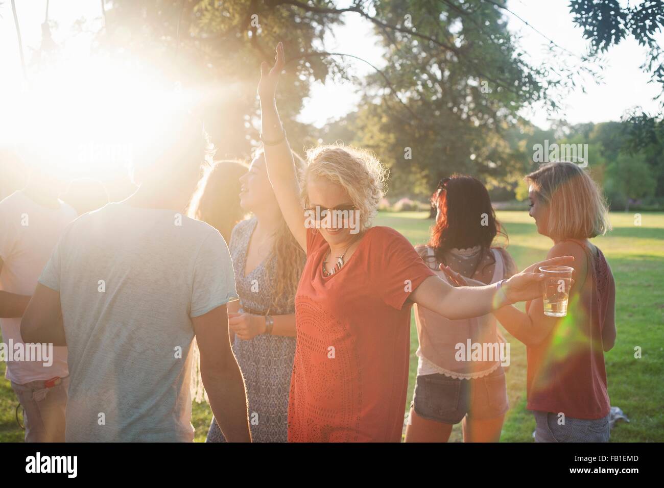 Adult friends dancing and drinking in park at sunset Stock Photo