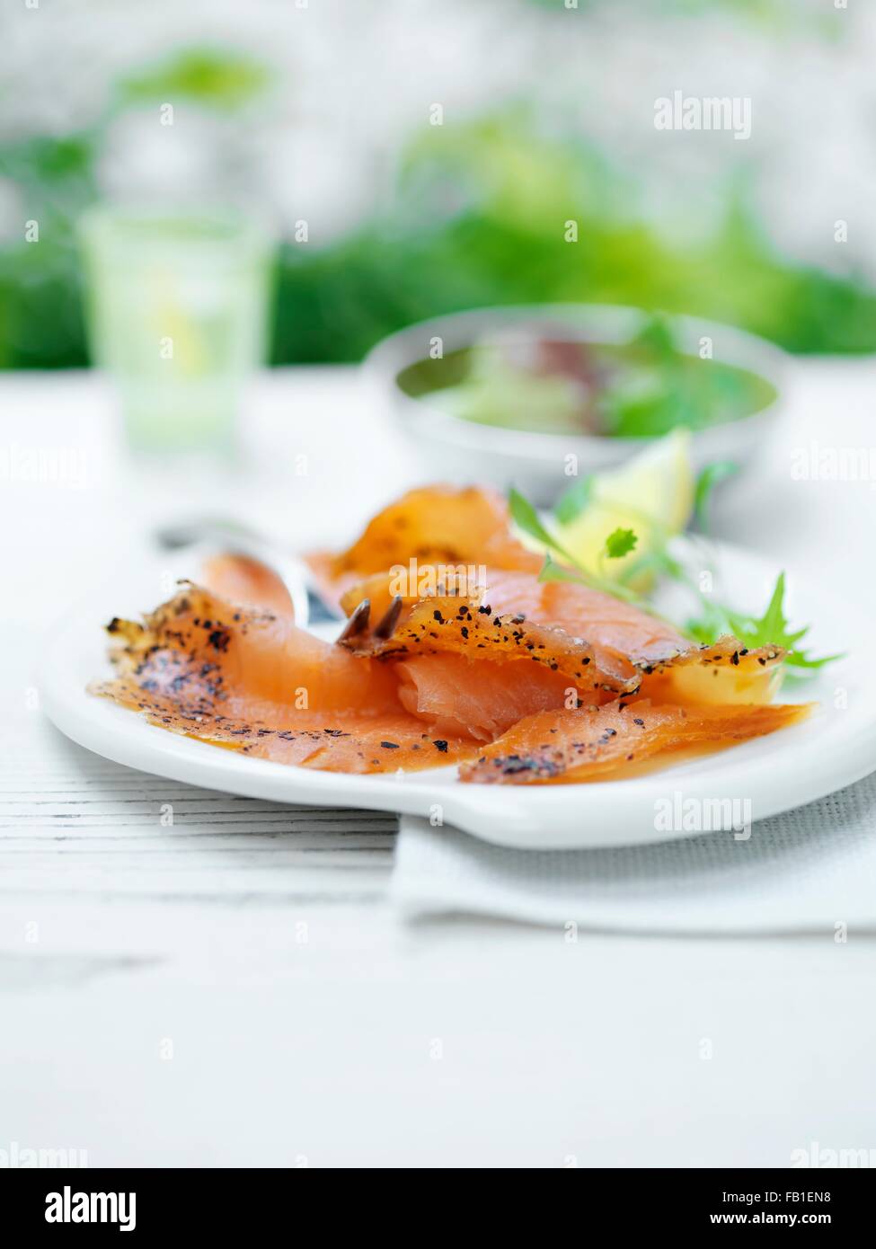 Deli salmon, with sliced lemon and green salad leaves Stock Photo