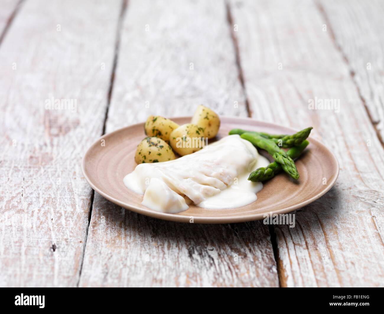 Two haddock fillets with a mornay sauce, served with asparagus and new