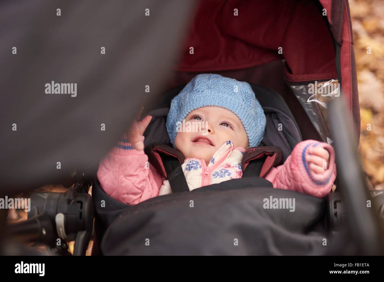 Baby girl wearing blue hat looking up from baby carriage Stock Photo