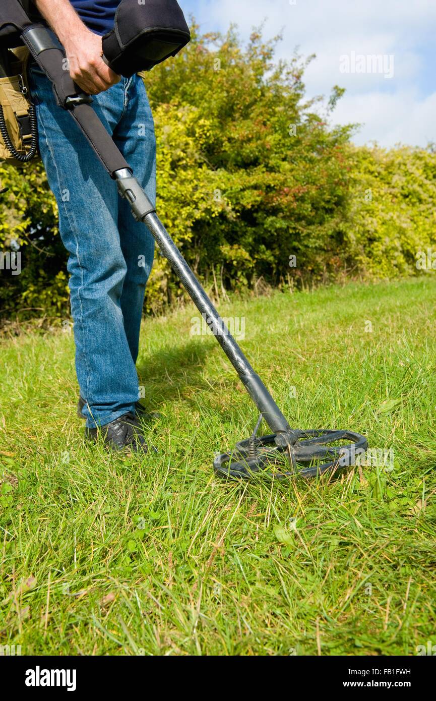 Cropped view of mature man searching grass using metal detector Stock Photo