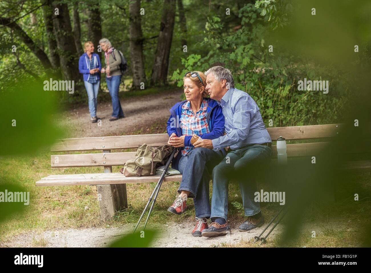 Couple sitting on bench in forest, looking at view Stock Photo