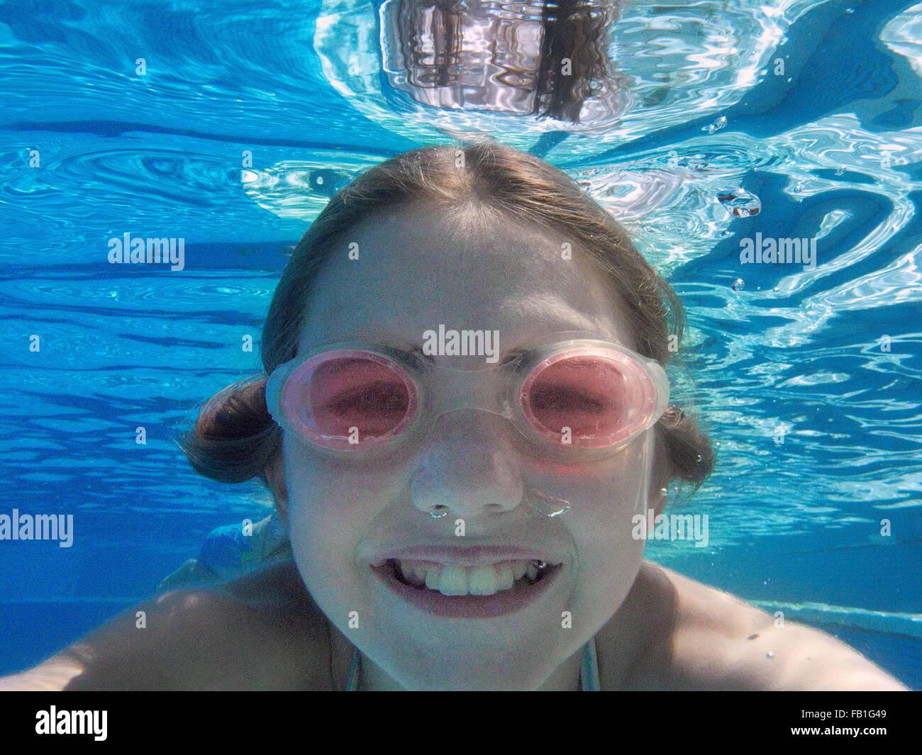 Close up underwater portrait of girl wearing goggles in swimming pool