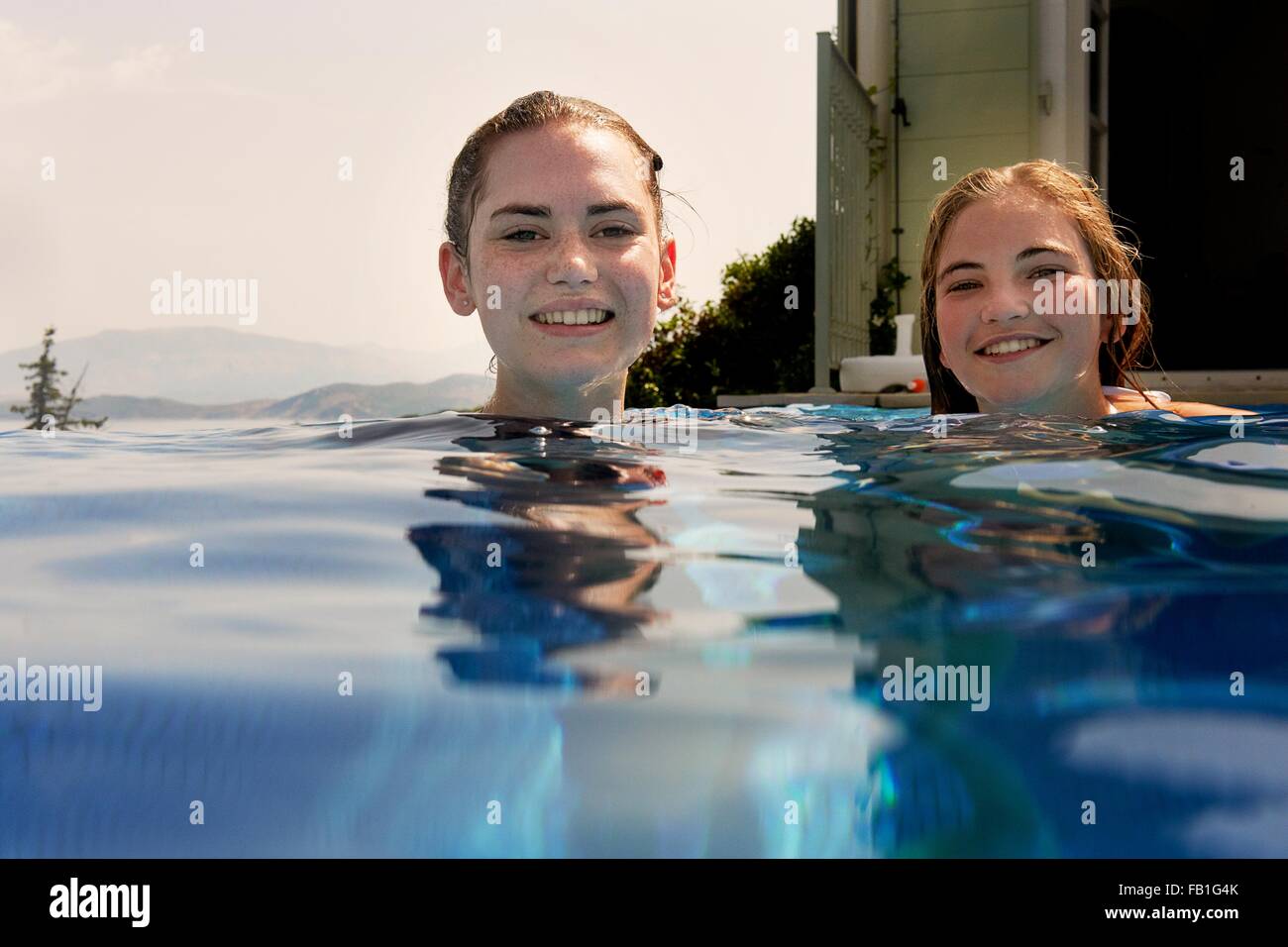 Surface level portrait of teenage girls in outdoor swimming pool Stock Photo