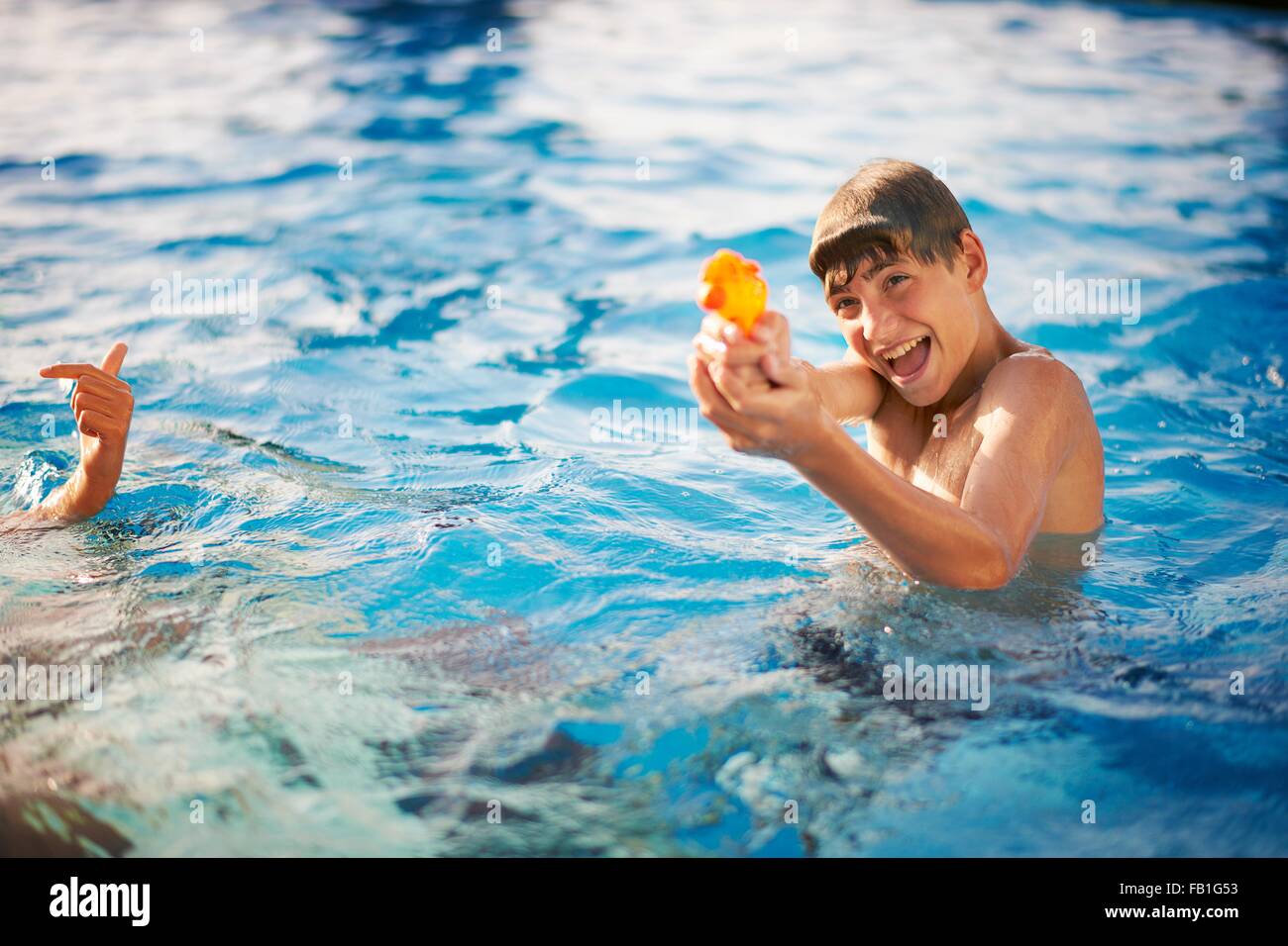 Boy squirting water pistol in outdoor swimming pool Stock Photo