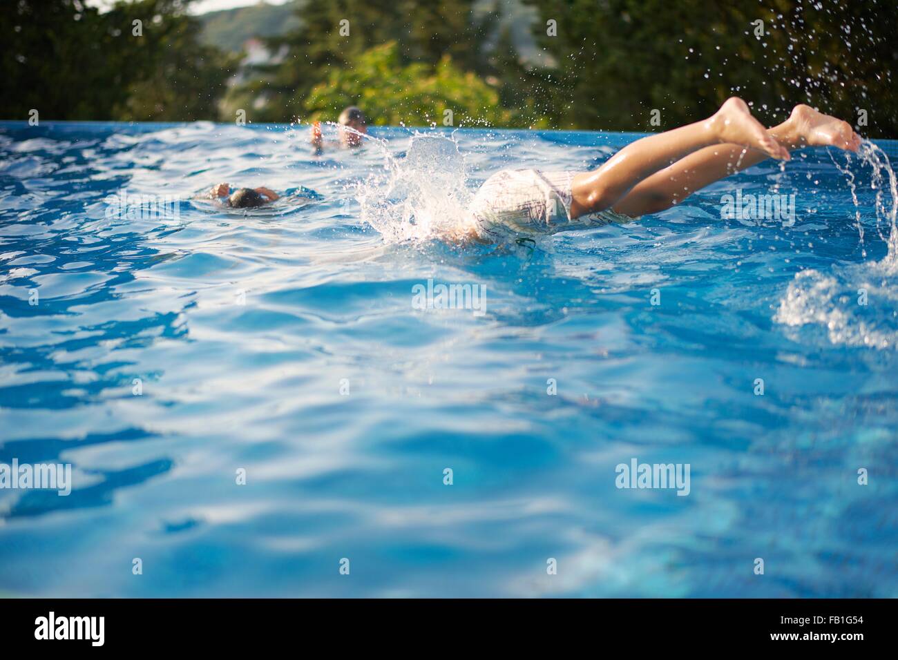 Boys diving into outdoor swimming pool Stock Photo