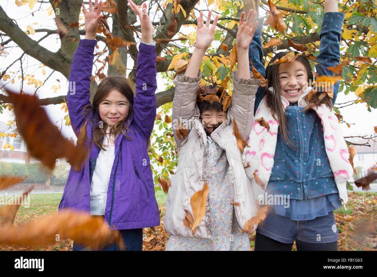 Portrait of three young girls throwing autumn leaves Stock Photo