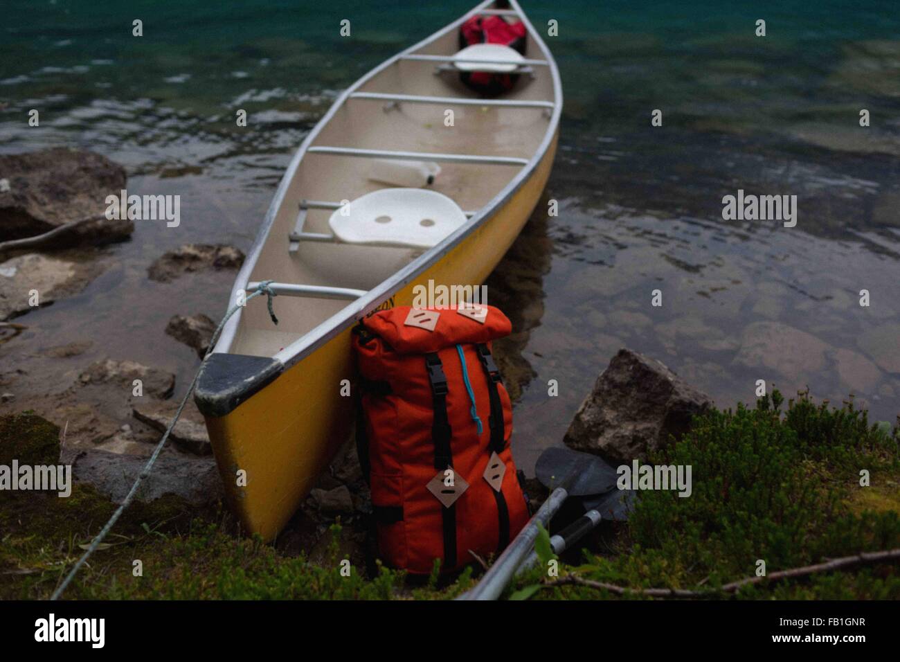 Orange colour backpack leaning against yellow canoe, Moraine lake, Banff National Park, Alberta Canada Stock Photo
