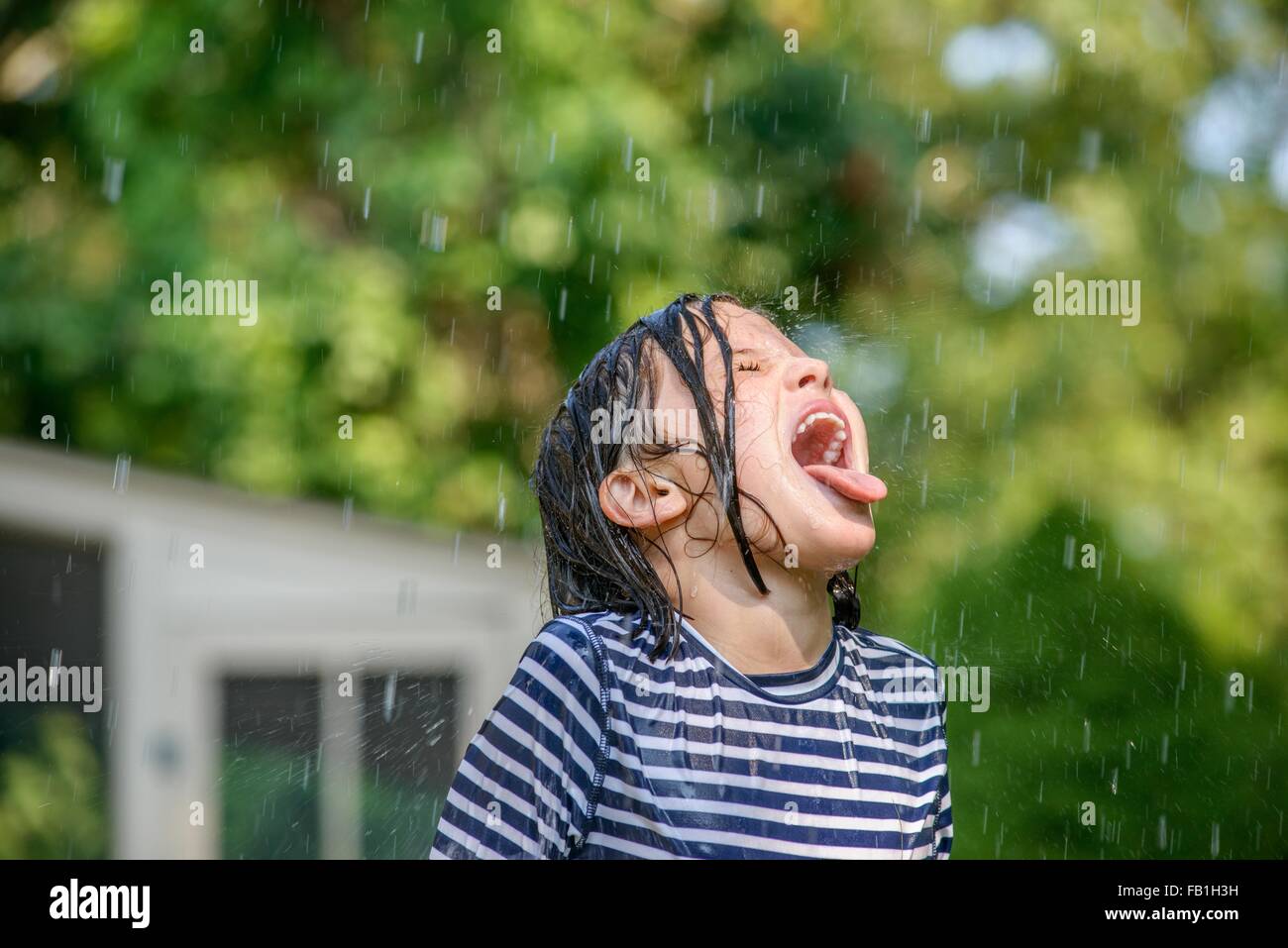 Young girl in garden, catching falling water in mouth Stock Photo