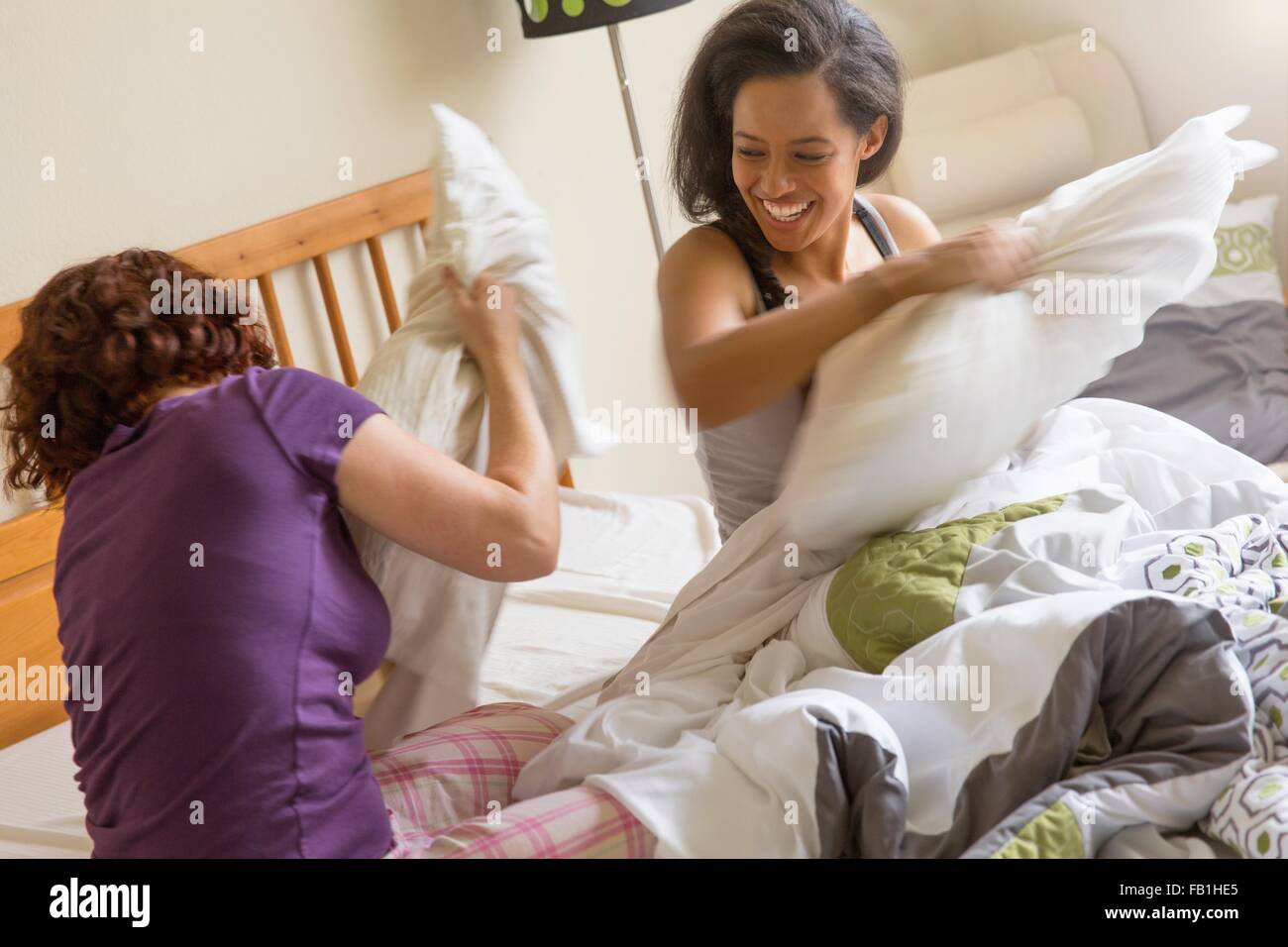 Friends on bed pillow fighting smiling Stock Photo