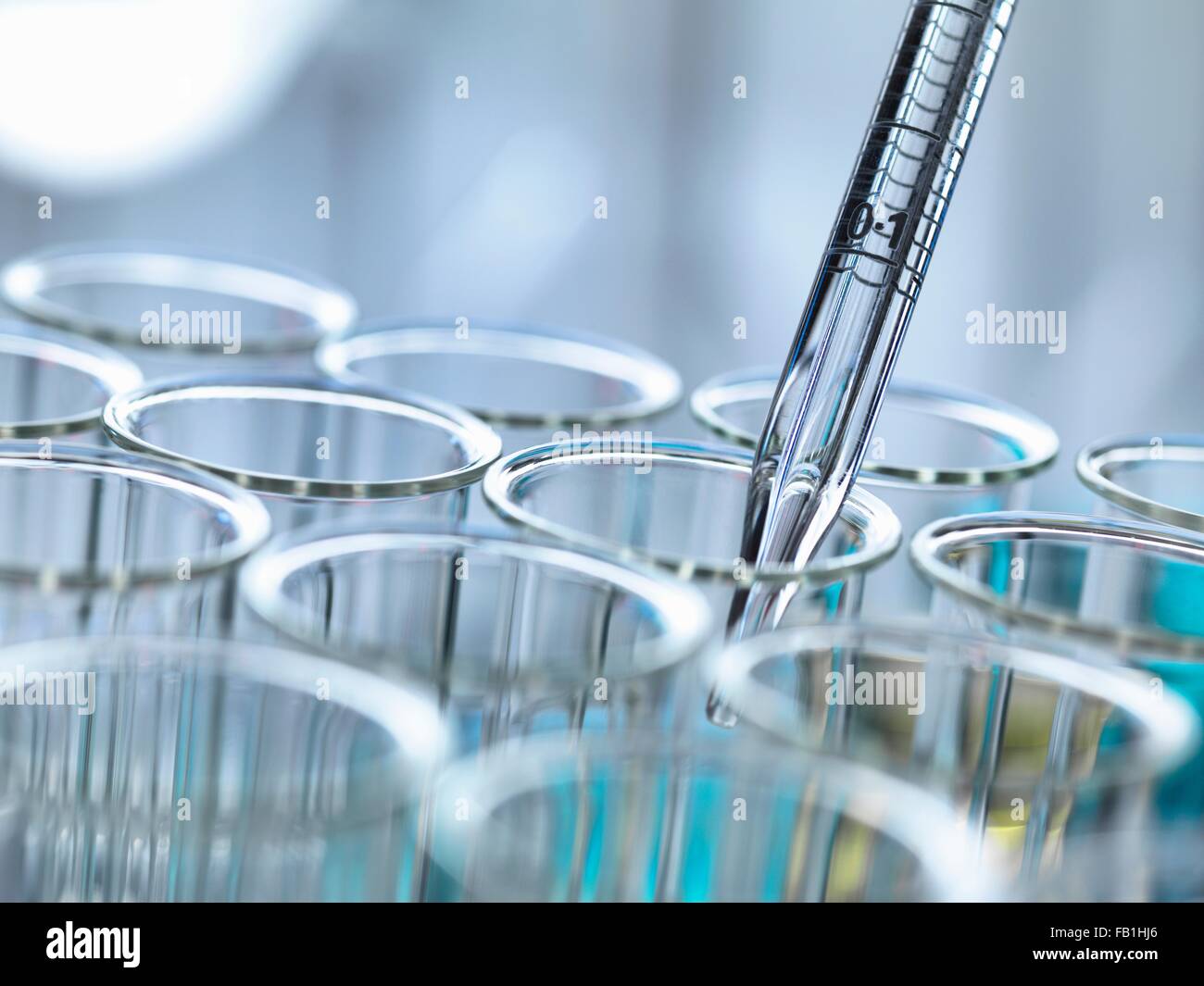 Cropped view of graduated pipette pipetting liquid into test tubes