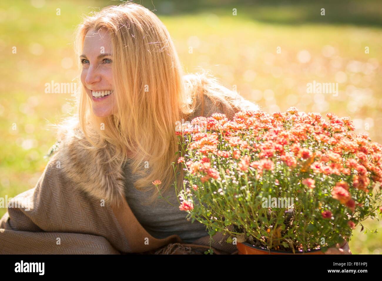Mature woman in sunlit garden with potted plant Stock Photo - Alamy
